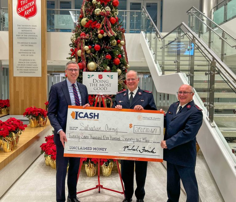 three men standing in front of a large christmas tree holding a giant check from iCash