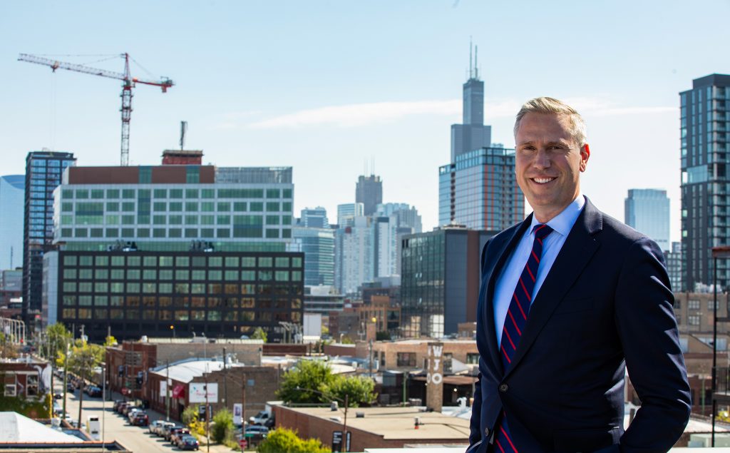 Half body portrait of Illinois Treasurer smiling against a backdrop of Chicago