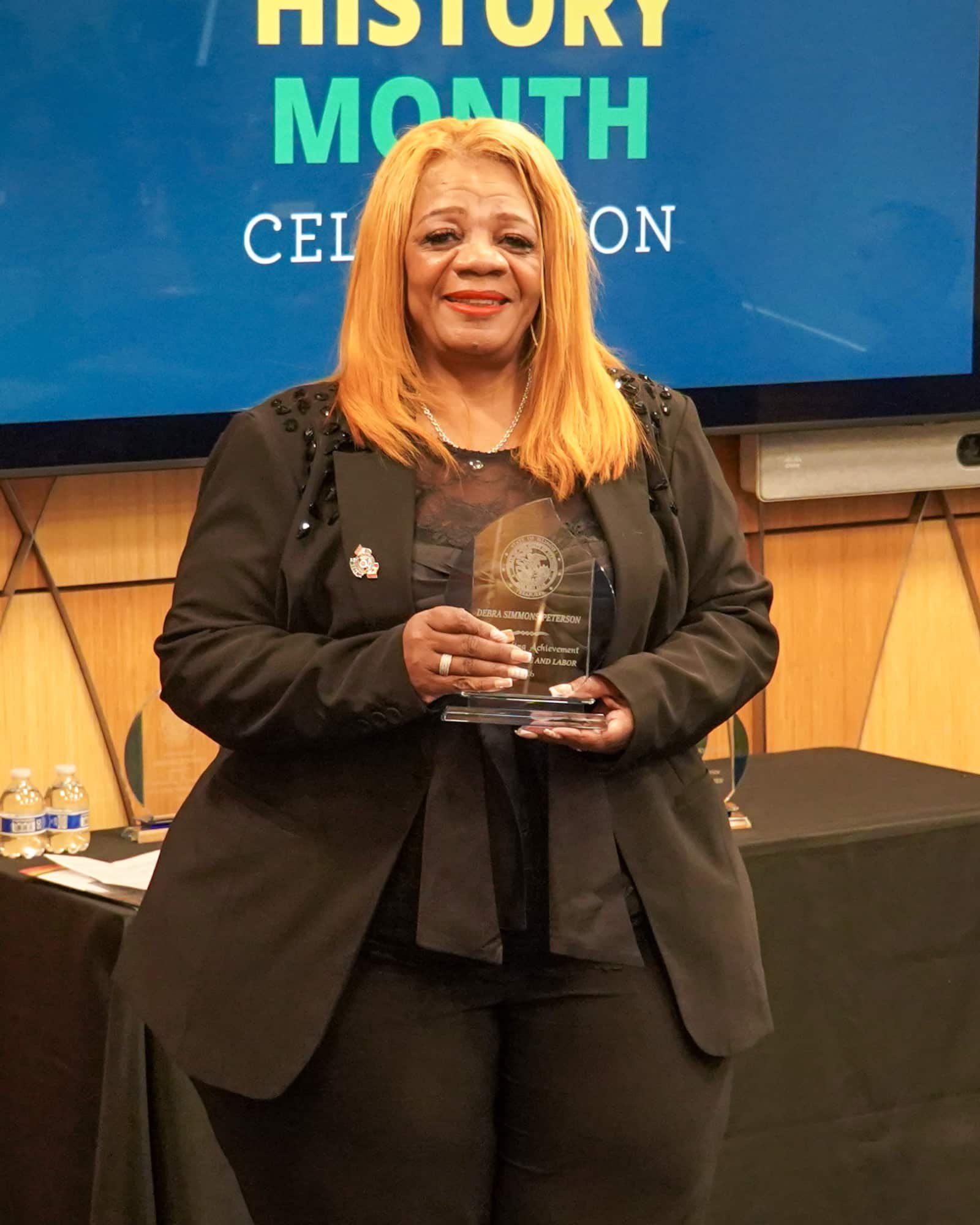 woman smiling holding award at ceremony