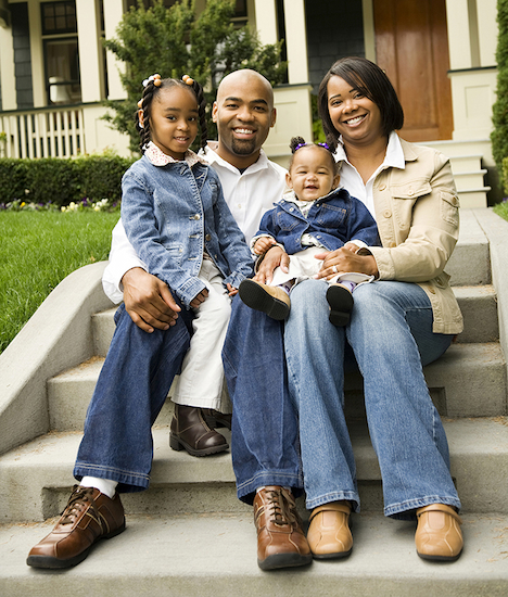 family smiling on the stoop outside their home
