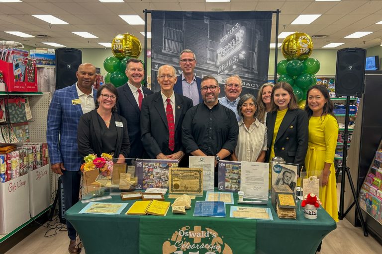a group of men and women dressed in professional clothes standing at a table of memorabilia