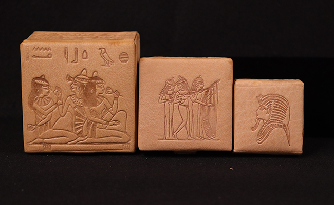 three Egyptian leather jewelry boxes with ancient-looking images carved in the leather